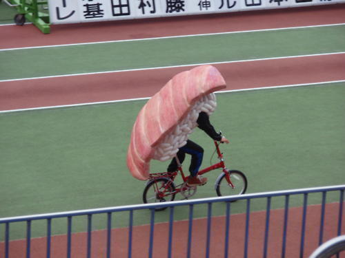 Person dressed as Sashimi riding a bicycle